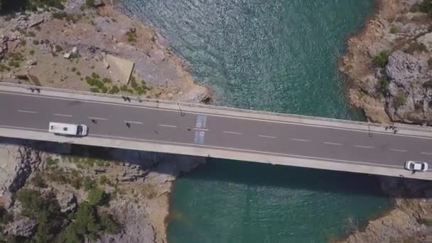 Luftaufnahme einer Brücke über das blaue Meer und Felsen. Clip. Sommer-Meereslandschaft mit türkisfarbenem Wasser und moderner Betonbrücke mit Touristen. — Stockvideo