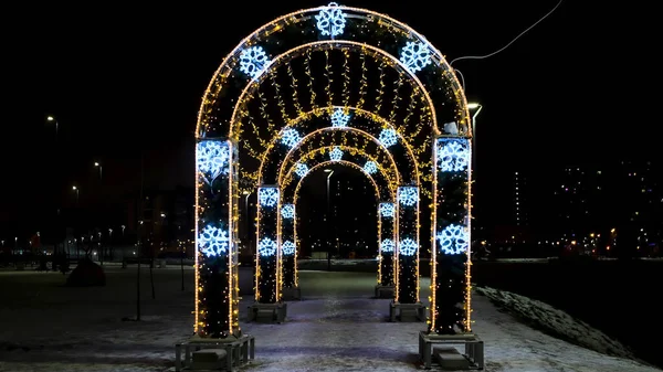 Tunnel à arc rond lumineux coloré dans un parc de la ville. Concept. Noël et Nouvel An un soir d'hiver avec une silhouette faite de guirlande brillante. — Photo
