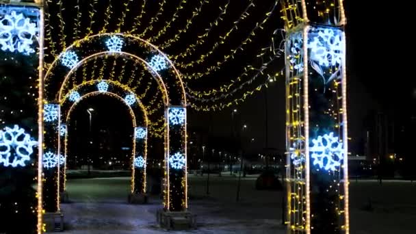 Kerstverlichting en decoraties in de straat van de stad in een vorm van bogen. Concept. Mooie lichten als symbool van de wintervakantie, stralende bloemenslinger op zwarte hemel achtergrond. — Stockvideo