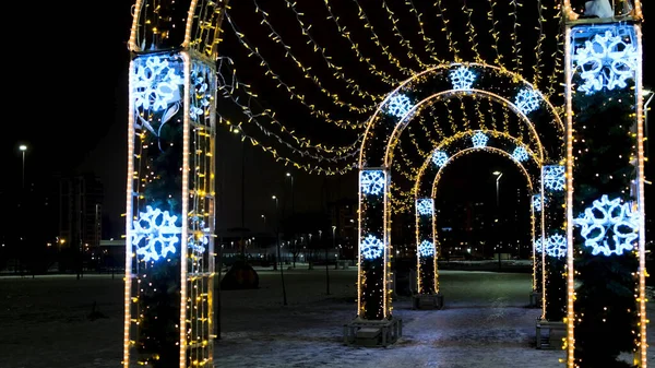 Illuminations et décorations de Noël dans la rue de la ville sous forme d'arcs. Concept. Belles lumières comme un symbole des vacances d'hiver, guirlande brillante sur fond de ciel noir. — Photo