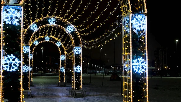 Colorful glowing round arch tunnel in a city park. Concept. Christmas and New Year eve on a winter evening with a figure made of shining garland. — Stock Photo, Image