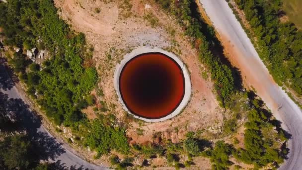 Top view of Sinkhole. Clip. Incredible natural phenomenon in form of sinkhole with brown water in field. Karst sinkhole with water near highway in field — Stock Video