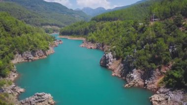 Güneşli bir günde Dağ Vadisi 'nin en güzel turkuaz nehri manzarası. Şarjör. Parlak turkuaz nehri ve yeşil köknar ağaçları olan güzel bir dağ manzarası. Orman bölgesindeki dağlarda turkuaz bir nehir.