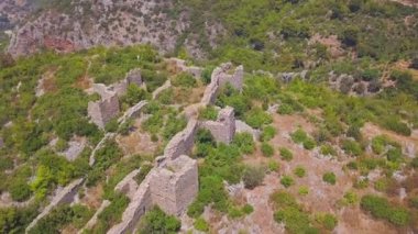 Tepedeki antik kale kalıntılarının en üst görüntüsü. Şarjör. Yeşil tepedeki kalenin güzel kalıntıları eski köyün üzerinde yükseliyor. Ormanlık dağlardaki antik şatonun tarihi kalıntıları.