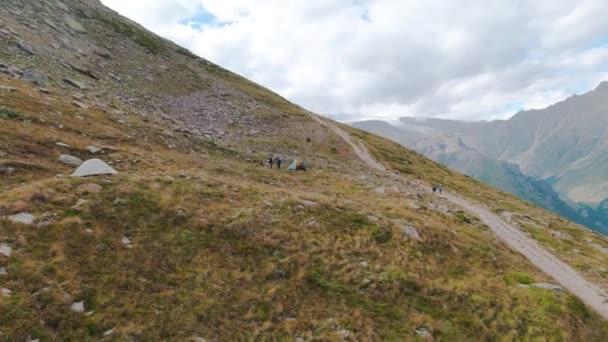 Campamento turístico en las montañas. Clip. Grupos de turistas activos hacen una parada en senderos de montaña para la recreación. Campamento para turistas escalando montañas en clima nublado en verano — Vídeos de Stock
