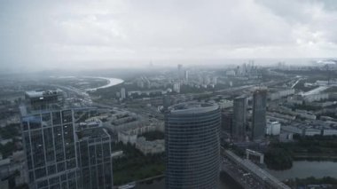 Sisli bir günde modern mimari kulelerinin gökdelenlerinin etkileyici panoramik manzarası. Başla. Nehir akan ve kıyıları boyunca büyüyen yeşil bitki örtüsü olan modern bir şehrin havadan görünüşü.. 