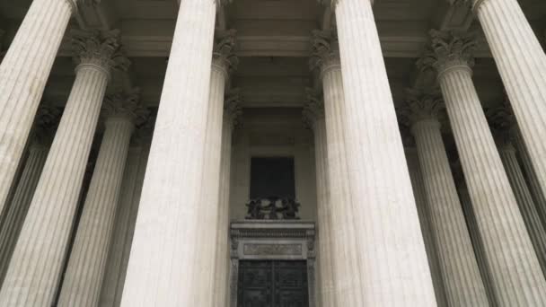 Grote gebeeldhouwde zuilen van wit marmer en een gigantische zwarte ijzeren deur. Actie. Details van een kathedraal of een tempel met zuilengalerij, concept van oude architectuur. — Stockvideo