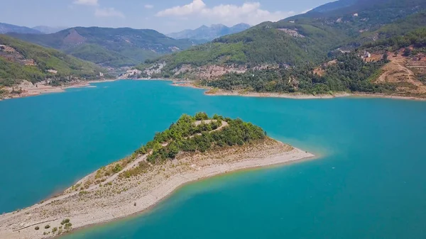 Top uitzicht op prachtige kaap in turquoise meer in de bergen. Een knip. Lange kaap strekt zich uit tot midden in het turquoise meer. Prachtige kaap in turquoise meer omgeven door bergen op zonnige zomerdag — Stockfoto