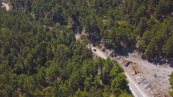 Vue de dessus de la voiture conduisant le long de serpentine de montagne. Clip. Suivez la voiture le long de la serpentine de montagne dans la zone boisée par une journée ensoleillée. Voyage à travers les zones montagneuses en voiture — Photo