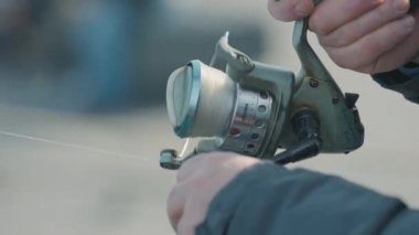 Balıkçıların oltaya takıldığı yakın çekim. Başla. Adam olta kamışını çeviriyor. Bulanık arkaplanda olta atmak