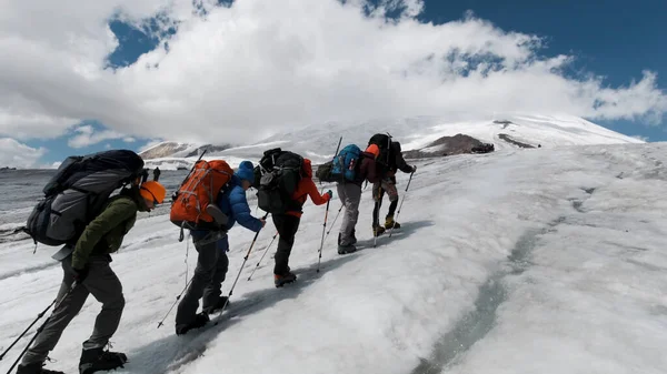 Drużyna wspinaczy wspina się na lodowate zbocze góry. Everest po drugiej stronie nieba. Klip. Ludzie cieszący się wspinaczką po śnieżnej ścieżce. — Zdjęcie stockowe