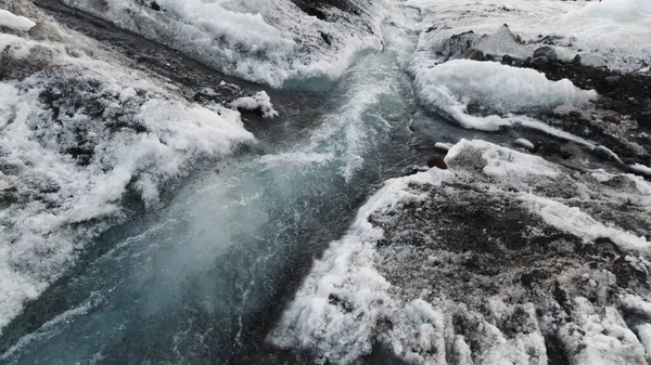 Gambe maschili che calpestano la bella acqua del flusso freddo. Clip. Camminando sul pendio innevato e ghiacciato della montagna con acqua blu pulita e fredda. — Foto Stock