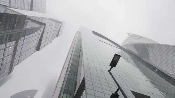 霧のような空の背景に息をのむようなガラスのファサードの高層ビルの下のビュー。行動だ。近代的な都市のジャングル、都市化と建築の概念. — ストック動画