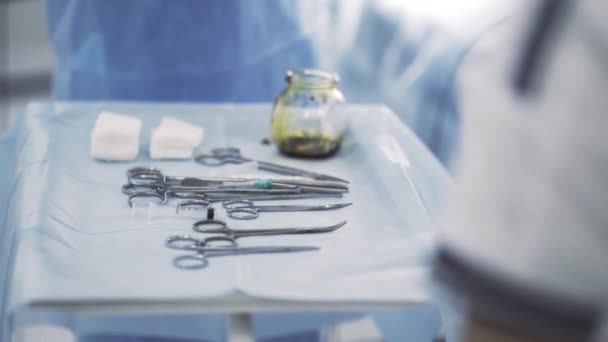 Fechar a mesa cirúrgica com instrumentos. Acção. Ferramentas médicas estéreis deitadas em uma mesa com uma tigela de iodo, conceito de medicina. — Vídeo de Stock