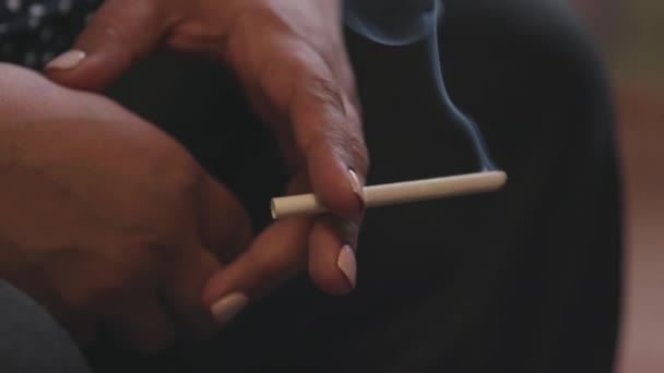 Close up of hand of fifty year old woman smoking a cigarette. Stock footage. Hands of senior woman with white manicure holding smoking cigarette, concept of fatigue. — Stock Video