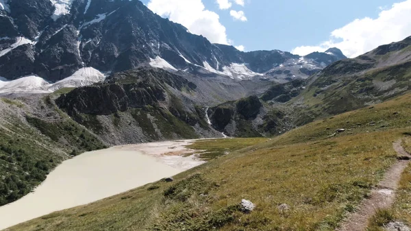 Widok z lotu ptaka na zielone pasmo górskie ze śnieżnymi szczytami w Kazbegi, Gruzja. Klip. Odkrywając piękno Ziemi, zielone zbocza i błękitne zachmurzone niebo. — Zdjęcie stockowe