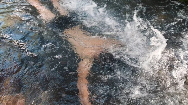 Ein Mann badet in einem kalten Gebirgsbach und hält seinen Kopf unter Wasser. Clip. Männchen hält beim Baden im kalten, schnellen Fluss den Atem an. — Stockfoto