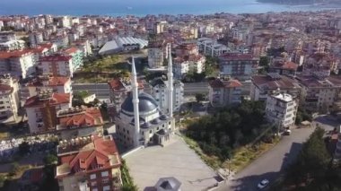 İstanbul, Türkiye 'de güzel bir cami manzarası. Şarjör. Deniz kenarındaki büyük bir kıyı şehrinin üzerinde uçuyor sokaklar, evler, sıcak güneşin altındaki yeşil bitki örtüsü.
