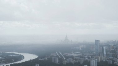 Büyük bir şehrin ve bükülen nehrin havadan görünüşü. Eylem. Sisli bir günde kurumsal binaların ve yerleşim alanlarının üzerinde uçmak..