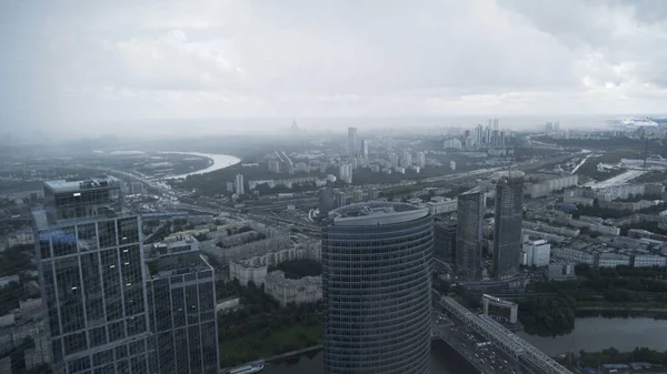 Впечатляющий панорамный вид на современную архитектуру башен небоскребов в туманный день. Начали. Вид с воздуха на современный город с текущей рекой и зеленой растительностью, растущей вдоль его берегов. — стоковое фото
