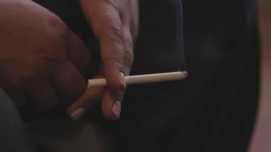 Sigara içen 50 yaşındaki bir kadının elini yakın çekim. Stok görüntüleri. Beyaz manikürlü, sigara içen, yorgunluk kavramı olan yaşlı bir kadının elleri..