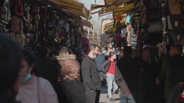 Τουρκία, Ιστανμπούλ-Δεκέμβριος 2020: Άντρας στο παζάρι με πλήθος κόσμου στο παρασκήνιο. Πάμε. Ο άνθρωπος στέκεται ανάμεσα σε περαστικούς ανθρώπους στο παζάρι την ηλιόλουστη μέρα. Ο άνθρωπος βλέπει τα πράγματα στο παζάρι. Μπαζάρ στην Τουρκία — Αρχείο Βίντεο