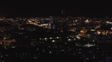 Büyük bir şehrin nefes kesici gece panoramik manzarası. Stok görüntüleri. Güzel aydınlatmalarla sokaklarda uçmak, sokak fenerleri ve kara gökyüzü arka planındaki binaların ışıkları.. 