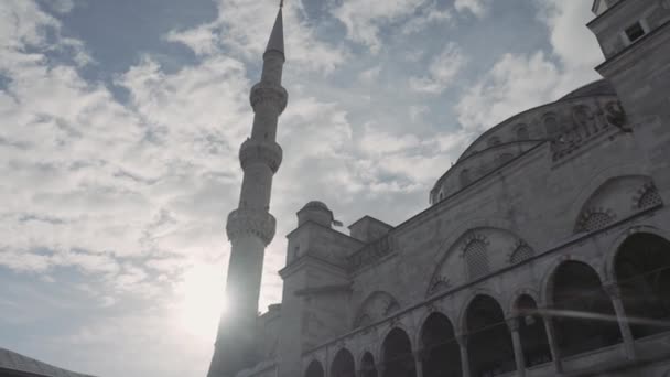 Bottom view of an ancient beautiful mosque on the background of blue cloudy sky and shining sun. Action. Concept of religion and architecture. — Stock Video