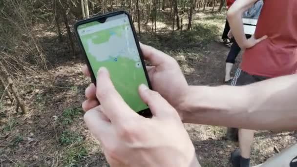 Közelkép férfi kezek ellenőrzése navigációs alkalmazás okostelefon az erdőben, utazási koncepció. Csípés. Túrázók csoportja digitális útvonaltérképet követve. — Stock videók