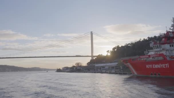 Turkije, Istanbul-december 2020: Schip voor de kust van zeestad. Actie. Steamboat vaart in de buurt van de kust van Istanbul op de achtergrond van hangbrug op zonnige dag. Schepen en stoomboten die voor de kust van — Stockvideo