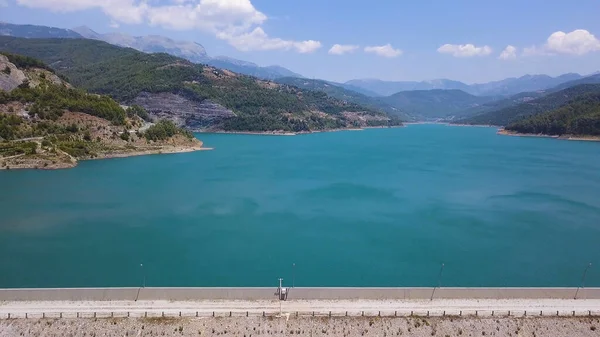 Luchtfoto van turquoise water in een bergmeer. Een knip. Turks landschap met waterreservoir van azuurblauwe kleur op de achtergrond van blauwe lucht en beboste heuvels. — Stockfoto