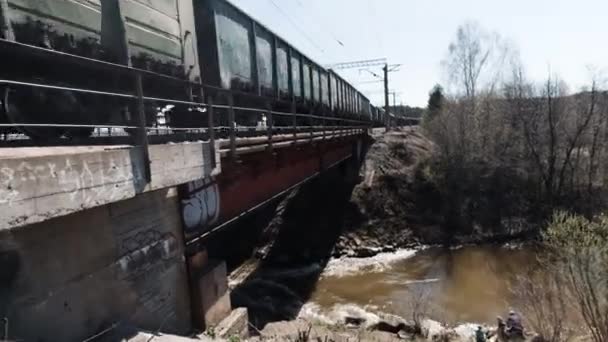 Вантажний поїзд з вугіллям. Кліп. Вантажний поїзд, що проходить швидко на невеликому мосту над брудною річкою, концепція перевезення . — стокове відео