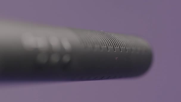 Recording microphone in audio recording studio. Action. Close up moving focus along the microphone stick with buttons isolated on lilac wall background. — Stock Video