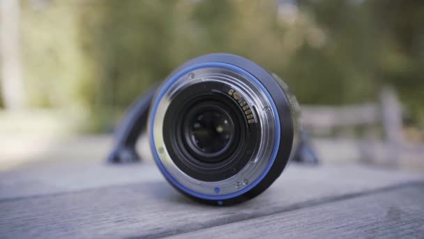 Primer plano de la lente de cámara profesional que se encuentra en una rotonda giratoria para niños. Acción. Concepto de fotografía. lente de cámara olvidada al aire libre sobre fondo borroso. — Vídeos de Stock