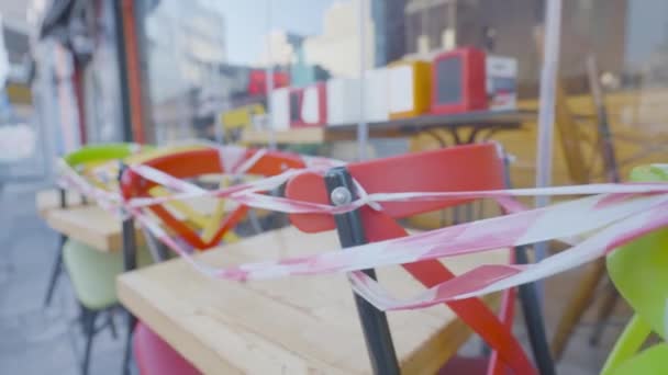 Straatcafés gesloten vanwege het coronavirus. Actie. Tafels en stoelen van outdoor cafe zijn verpakt met tape. Gesloten cafés tijdens pandemie en algemene quarantaine — Stockvideo