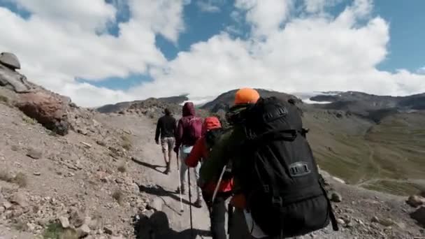 Vista traseira de viajantes subindo uma encosta de montanha com paus para rastreamento. Clipe. Esporte extremo e conceito de estilo de vida ativo, explorando a beleza do mundo. — Vídeo de Stock