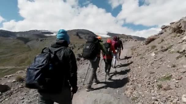 Caminhantes caminham ao longo da estrada no desfiladeiro da montanha. Clipe. Fundo natural de tirar o fôlego com um grupo de turistas caminhando um por um na região montanhosa. — Vídeo de Stock