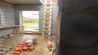 Kırsal tuğla ev yapım aşamasında. Şarjör. Duvarları tuğlalı, pencereleri ve şantiyesi olan inşa edilmemiş kulübenin içi..