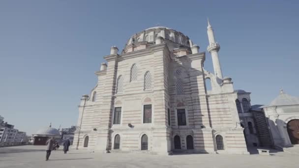 Bottom rear view of a giant muslim mosque on blue sky background. Action. Massive historic building and people walking on a city square. — Stock Video