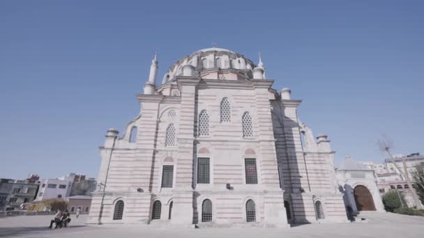 Vista posteriore inferiore di una moschea musulmana gigante su sfondo cielo blu. Azione. Massiccio edificio storico e persone che camminano su una piazza della città. — Video Stock