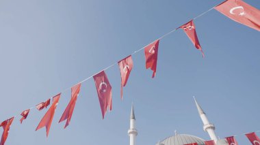 Türkiye, İstanbul-Aralık 2020: Mavi arka planda Türk bayrakları. Başla. Rüzgarda dalgalanan Türk bayraklarıyla şenlikli kurdele. Türk bayrakları minarelerin arka planında şenlikli ipe asılıyor
