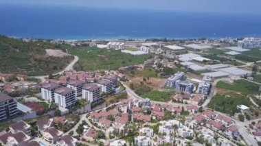Büyük bir otel kompleksinin havadan görünüşü, yeşil bitki örtüsü ve sonsuz deniz arka planında yerleşim binaları. Şarjör. Yaz tatili ve tatil kavramı.