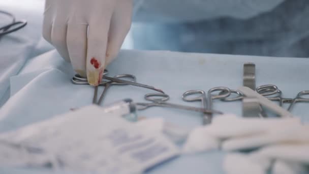 Sluiten van steriel chirurgisch gereedschap op een dienblad in de operatiekamer. Actie. Hand van een arts in beschermende handschoen met menselijk bloed vlekken nemen van een speciaal instrument voor de operatie. — Stockvideo