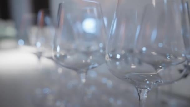 Κοντινό πλάνο με πολλά ποτήρια κρασιού για κρασί και σαμπάνια. Πάμε. Banquet σειρά από άδεια ποτήρια κρασιού για ποτά πριν από τις διακοπές. Γραμμές κενών ποτηριών κρασιού στο τραπέζι δεξιώσεων — Αρχείο Βίντεο