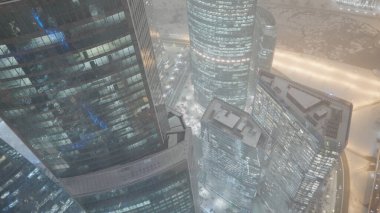 Geceleri kar yağan gökdelenler. Başla. Gece pencerelerinde güzel gece lambaları olan gökdelenlerin en iyi manzarası. Geceleri kar fırtınasında parlayan gökdelenlerin çatıları