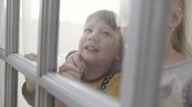 Küçük bir çocuk ve kız kapının arkasında cam parçalarıyla dikiliyorlar. Başla. Kız ve erkek kardeş kapının arkasında birlikte heyecanlı duruyorlar. Küçük kız ve erkek çocuk kapının arkasında duruyorlar.