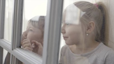 Küçük bir çocuk ve kız kapının arkasında cam parçalarıyla dikiliyorlar. Başla. Kız ve erkek kardeş kapının arkasında birlikte heyecanlı duruyorlar. Küçük kız ve erkek çocuk kapının arkasında duruyorlar.