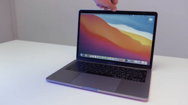New York - ABD, 02.20.2021: Yeni Mac Apple dizüstü bilgisayarını gösteren erkek eline yakın çekim. Başla. Beyaz masada duran yeni bir MacBook Pro sunumu.