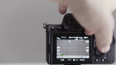 Gri duvar arka planında izole edilmiş yeni bir fotoğraf makinesinin hareket edebilen görüntüsünü erkek elinin kapatması. Başla. Çekimden önce hazırlık yapıyorum..