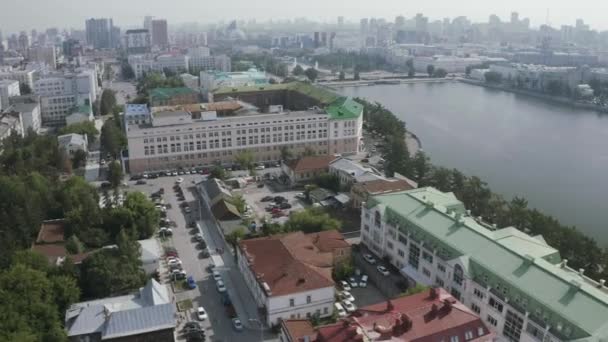 Widok z lotu ptaka na centrum miasta i szeroką rzekę. Materiał filmowy. Panoramiczny widok na letnie miasto z ulicami ozdobionymi zielonymi drzewami i budynkami administracyjnymi. — Wideo stockowe